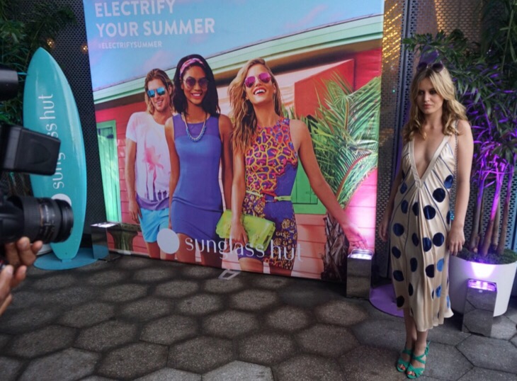 Georgia May Jagger poses in front of her Electrify Your Summer Campaign with Sunglass Hut